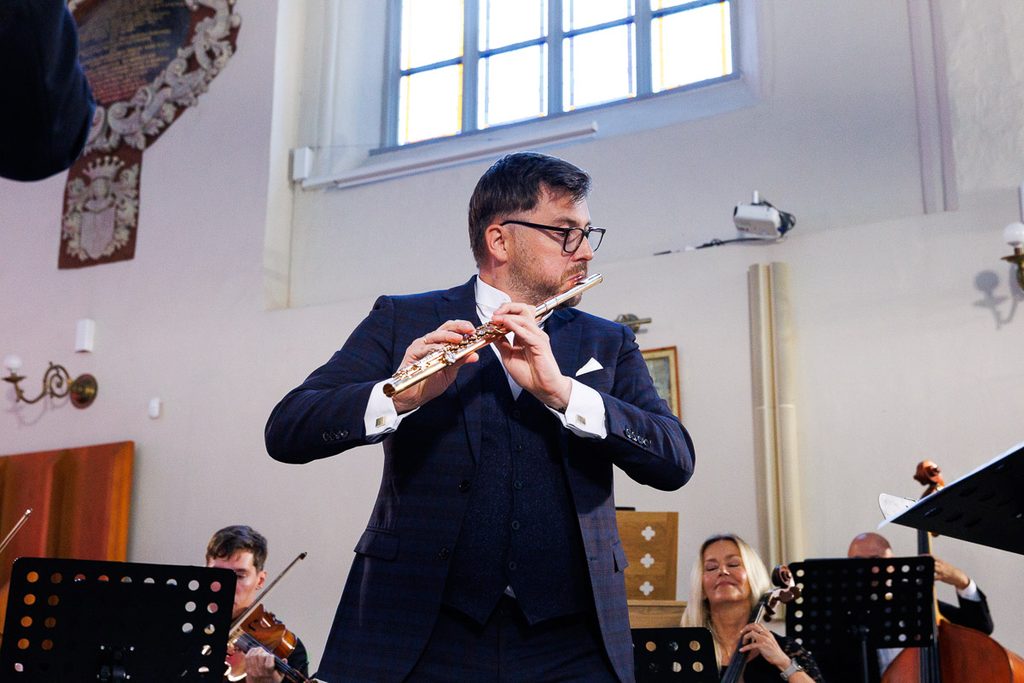Łukasz Długosz, flecista, podczas koncertu w kościele – fotografia muzyka klasycznego w trakcie występu.