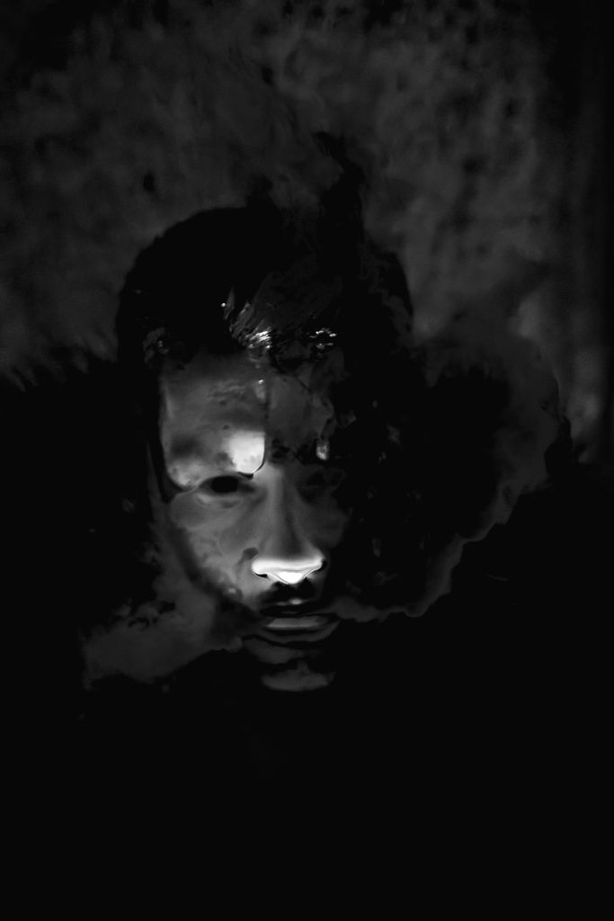 Ekspresyjny portret twarzy częściowo ukrytej w głębokim cieniu – artystyczna fotografia portretowa oparta na kontraście światła.