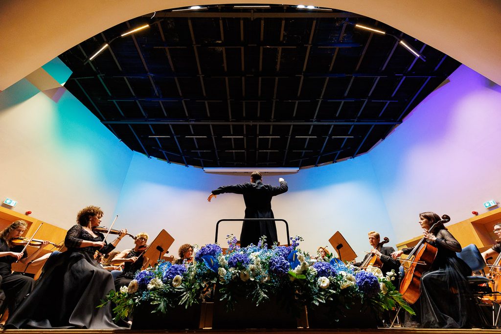 Dyrygent prowadzący orkiestrę symfoniczną podczas koncertu w Filharmonii Zielonogórskiej – profesjonalna fotografia koncertowa.