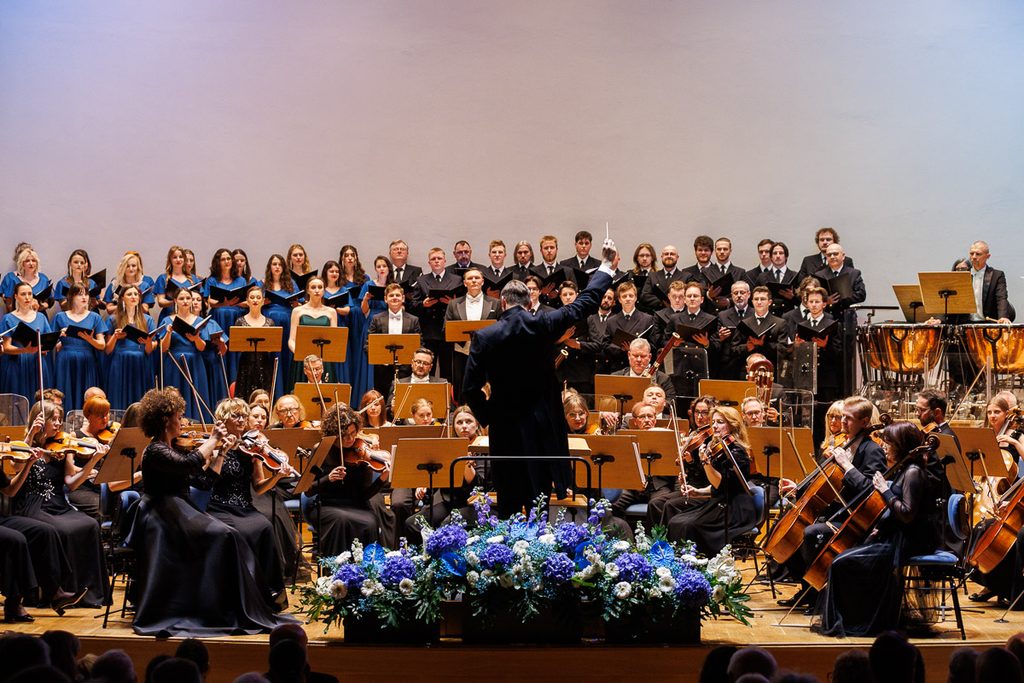 Dyrygent Filharmonii Zielonogórskiej prowadzący orkiestrę i chór podczas uroczystego koncertu.