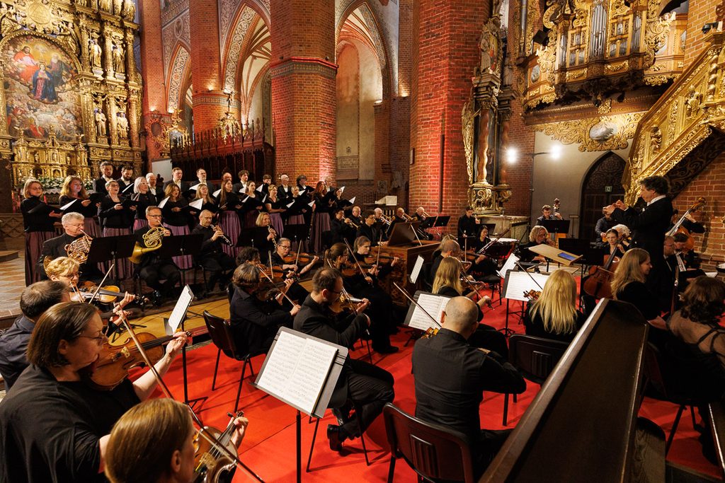 Orkiestra i chór podczas koncertu w Pelplinie – fotografia muzyki klasycznej w zabytkowym wnętrzu.