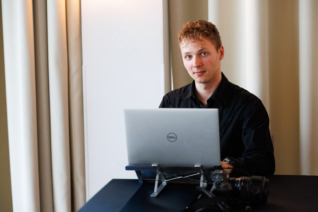 Paweł Lach, fotograf i śpiewak operowy z Gdańska, podczas pracy przy laptopie i sprzęcie fotograficznym.