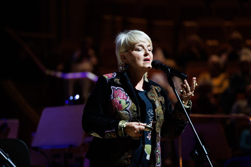 Krystyna Stańko podczas koncertu jazzowego – wokalistka śpiewająca do mikrofonu na scenie, uchwycona w trakcie muzycznego występu.